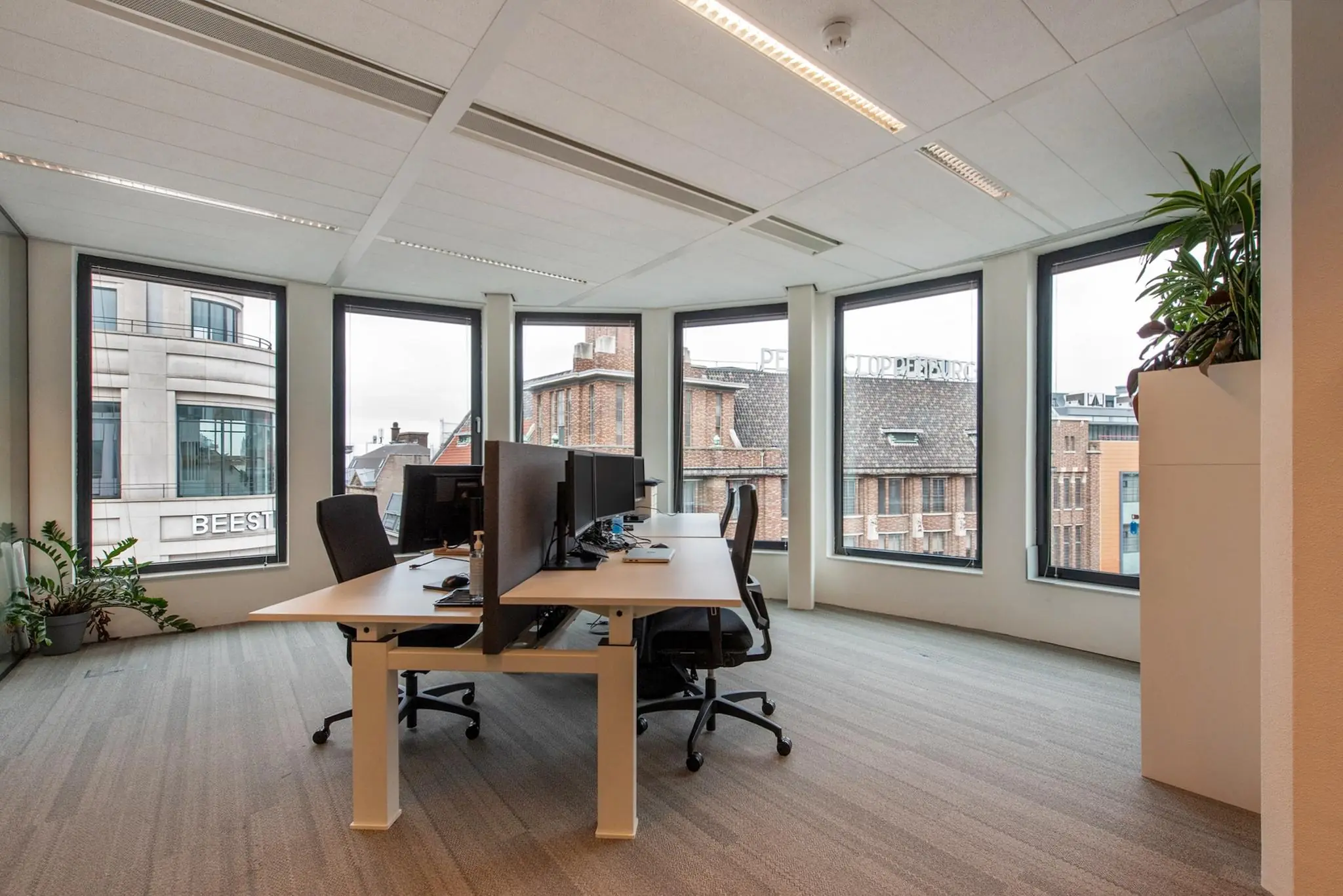 Modern kantoor met werkplekken en uitzicht op de Grote Marktstraat in Den Haag.